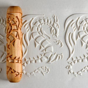 May include: A wooden rolling pin with a dragon design. The rolling pin is used to create decorative patterns in dough.