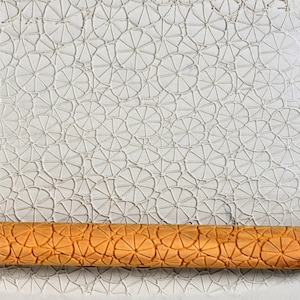 Könnte beinhalten: Ein Nudelholz aus Holz mit einem detaillierten Blumenmuster. Das Nudelholz ist aus hellem braunem Holz gefertigt und hat eine glatte, polierte Oberfläche. Das Muster ist filigran und zeigt ein sich wiederholendes Muster aus Blumen und Blättern.