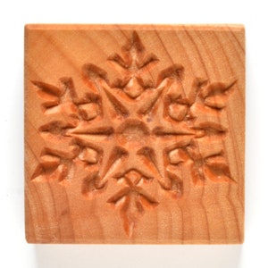 May include: A wooden snowflake cookie cutter with a detailed design. The cutter is made of light brown wood and has a smooth finish.