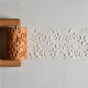 May include: A wooden rolling pin with a floral design. The rolling pin is used to create embossed patterns on dough.