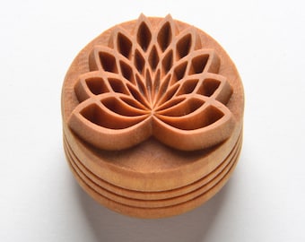May include: A wooden stamp with a detailed carving of a lotus flower. The stamp is round and has a natural wood finish.
