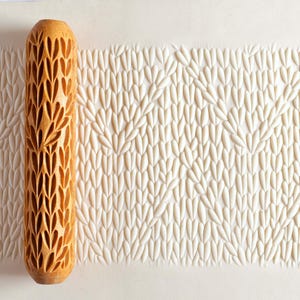 May include: A wooden rolling pin with a carved pattern of leaves and a knitted stitch design. The rolling pin is used to create an embossed pattern on fondant or dough.