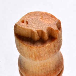 May include: A wooden stamp with a fish design. The stamp is made of light brown wood and has a smooth surface.