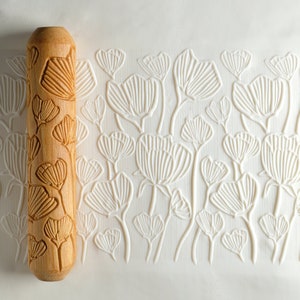 May include: A wooden rolling pin with a floral design. The rolling pin is used to create patterns in fondant or dough.