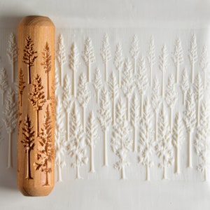 May include: A wooden rolling pin with a repeating pattern of pine trees carved into the surface. The rolling pin is used to create an embossed design on fondant or dough.