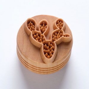 May include: A wooden stamp with a detailed carving of a cactus plant. The cactus has a prickly texture and is carved in a light brown color.