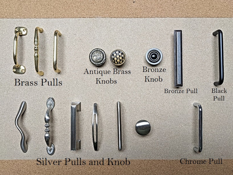 May include: A collection of cabinet hardware, including brass pulls, antique brass knobs, a bronze knob and pull, a black pull, silver pulls and a knob, and a chrome pull. The hardware is displayed on a neutral background.
