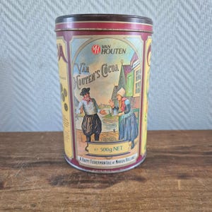 May include: Vintage Van Houten's Cocoa tin with a maroon lid and base. The label features a colorful illustration of a man and woman in traditional Dutch attire. The tin reads "Van Houten's Cocoa" and "e 500g NET".