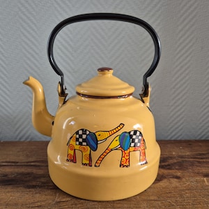 May include: Yellow enamel teapot with a black handle and spout. The teapot features a lid and is decorated with two colorful elephants. The elephants have checkered ears and trunks, and are outlined in black.