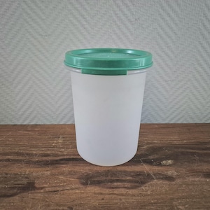 May include: A clear plastic container with a green lid. The container is cylindrical and has a smooth surface.