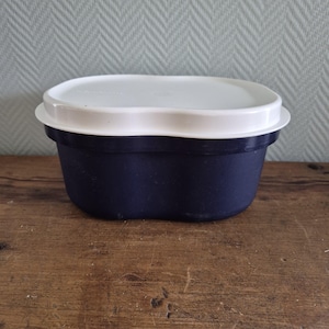 Op de afbeelding: Een blauwe en witte plastic broodtrommel met een golvend deksel. De broodtrommel is ovaalvormig en heeft een glad oppervlak.