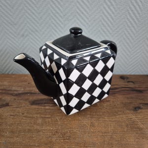Op de afbeelding: Een zwart-witte geblokte theepot met een vierkante vorm. De theepot heeft een zwart deksel en tuit, en een kleine handgreep. Het dambordpatroon voegt een vleugje elegantie toe aan de keuken.