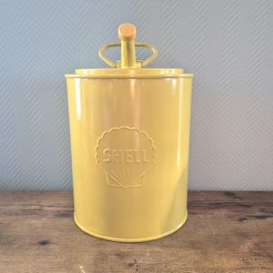 Puede incluir: Bidón de aceite de metal amarillo con un logotipo de Shell negro y amarillo y un pico de plástico amarillo.