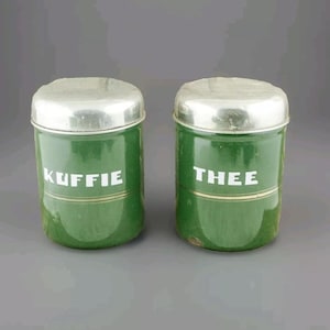 May include: Two vintage green metal canisters with silver lids. The canisters are labeled "Koffie" and "Thee".