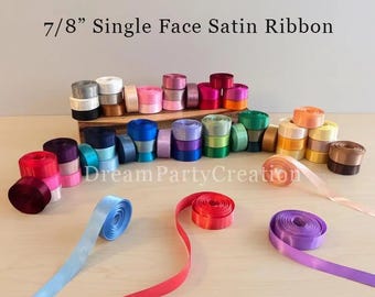 May include: A collection of 2.2 cm single face satin ribbon spools in various colours including red, blue, purple, pink, and brown. The text 7/8" Single Face Satin Ribbon and DreamPartyCreation are visible in the image.