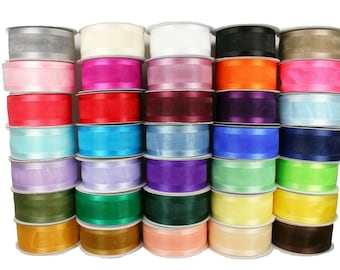 May include: A collection of 24 spools of satin ribbon in various colors, including silver, white, pink, red, blue, purple, green, yellow, brown, and beige. The ribbon is arranged in rows, with each spool stacked on top of the other.