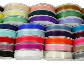 May include: A collection of 24 spools of sheer ribbon in various colors, including black, white, red, blue, green, and purple. The ribbon is wound around cardboard spools.