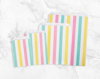 May include: Four paper treat bags in varying sizes, arranged from smallest to largest. Each bag features vertical stripes in pastel colors: pink, yellow, and teal, alternating with white stripes. The bags are made of paper and have a folded top.