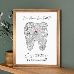 May include: Framed print with a gold border. The print features a map in the shape of a tooth, with a red heart marking a location. Text at the top reads "Dr. Jenna Lee, DMD" and at the bottom, "Congratulations! You deserve a crown."