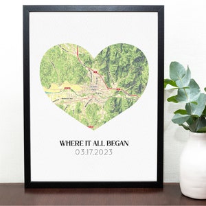 May include: Framed print featuring a heart-shaped map of Grants Pass, Oregon, in shades of green and tan. The text "WHERE IT ALL BEGAN 03.17.2023" is printed below the map in a simple font. The print is in a black frame.