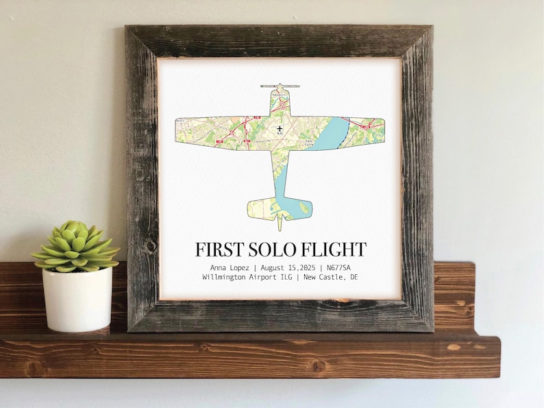 May include: A framed print featuring an airplane silhouette overlaid with a map design. The text "FIRST SOLO FLIGHT" is displayed below the image, along with the name Anna Lopez, date, and airport information. The frame is made of weathered wood.