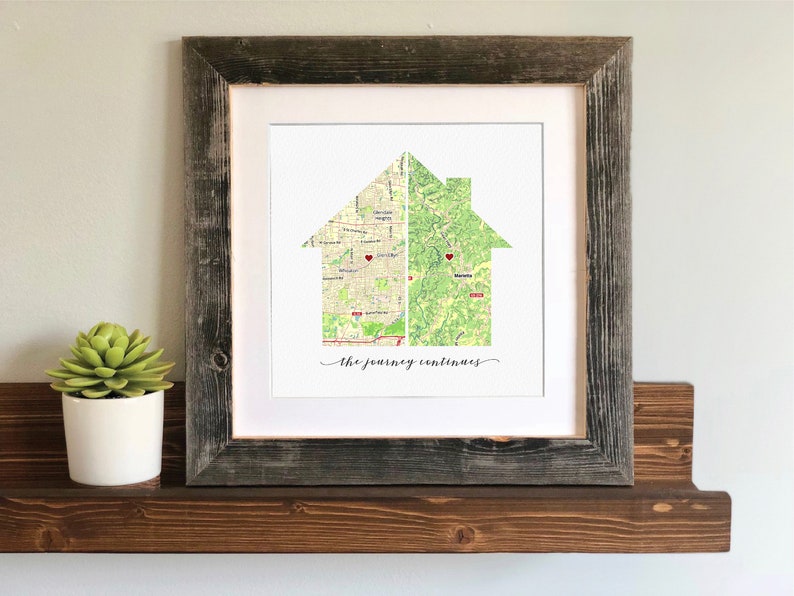 May include: A framed print of a house silhouette made from two maps. The house is divided in half, with each half showing a different map. The text "The journey continues" is printed below the house.