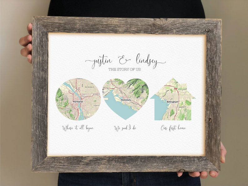 May include: A framed print with a map of three locations, titled "Justin & Lindsey, The Story of Us". The locations are Portland, Honolulu, and Bellingham. The map of Portland is in a circle, Honolulu is in a heart shape, and Bellingham is in a house shape. The text below each map reads "Where it all began", "We said I do", and "Our first home".