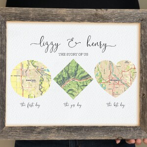 May include: A framed print with a white background and three maps. The maps are in a circle, diamond, and heart shape. The text "Lizzy & Henry" is at the top of the print. The text "The Story of Us" is below the names. The text "The first day", "The yes day", and "The best day" are below the maps.