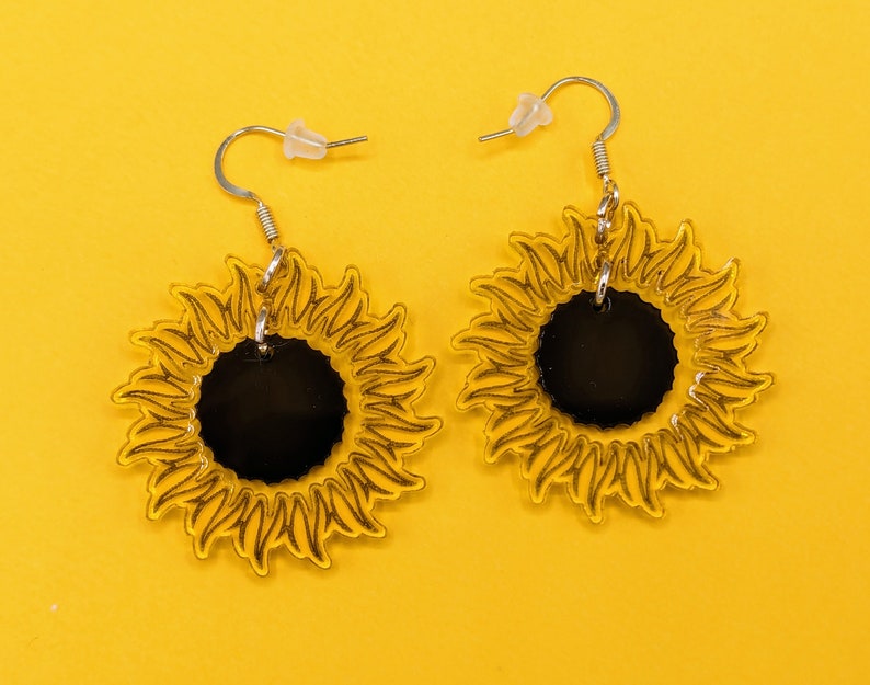 May include: A pair of yellow sunflower earrings with black centres. The earrings are made of acrylic and have a simple silver hook fastening.