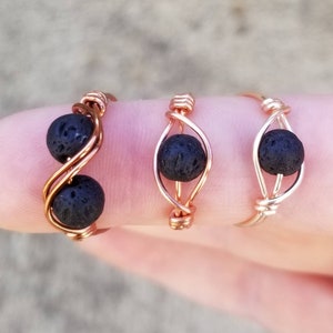 May include: Three wire wrapped rings with black lava rock beads. The rings are made with copper wire and are available in different styles.