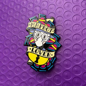 May include: A colorful enamel pin featuring a cartoon character with glasses and a hat. The pin has a banner that reads "MAPBOT LOVER" and a yellow padlock with the number "1". The pin is set against a purple background.