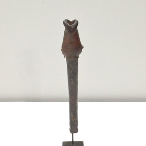 May include: A dark brown ceramic pipe with a flared opening at the top, mounted on a black metal stand.