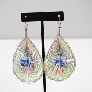 May include: A pair of teardrop-shaped earrings with a silver wire frame and a colorful, swirling pattern inside.