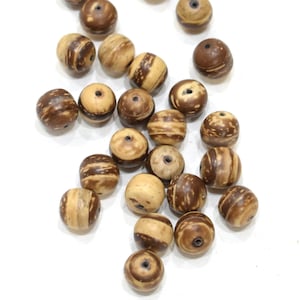 May include: A collection of brown and beige wooden beads with a natural wood grain pattern. The beads have a small hole in the centre for stringing.