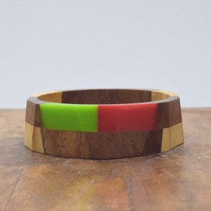 May include: A wooden ring with green and red resin inlay. The ring is made of different types of wood, including walnut and maple.