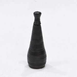 Puede incluir: Un tapón de botella de madera negro con una parte superior redondeada y un diseño acanalado.