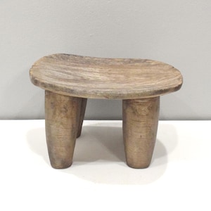 Puede incluir: Una taza de cerámica blanca con un asa negra y el texto "But First, Coffee" en negrita negra. La taza se encuentra sobre un fondo borroso, resaltando su diseño simple.