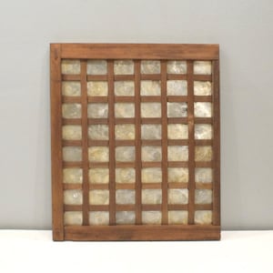 May include: A square wooden frame featuring a grid pattern with thin brown slats. The grid contains multiple small, translucent, off-white square tiles made of natural shell material, creating a mosaic effect within the wooden structure.