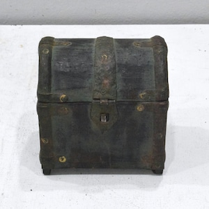 Puede incluir: Un pequeño cofre del tesoro de madera verde oscuro con detalles metálicos y una tapa con bisagras. El cofre tiene un diseño sencillo con una cerradura y una cerradura.