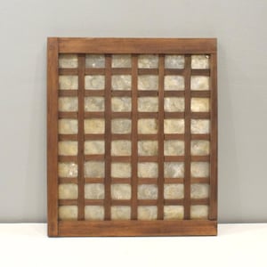 May include: A square wooden frame featuring a grid pattern with thin brown slats. The grid contains multiple small, translucent, off-white square tiles made of capiz shell, arranged in a uniform pattern within the wooden structure.