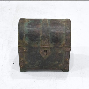 Op de afbeelding: Een kleine, donkere houten kist met metalen accenten en een scharnierend deksel. De kist heeft een versleten, antieke uitstraling en is versierd met groene en bruine verf.