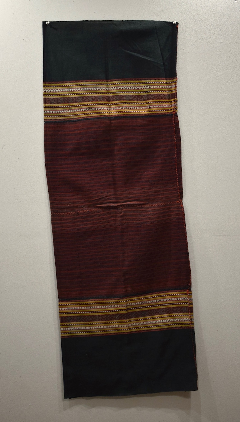 K&ouml;nnte beinhalten: Ein dunkelroter und schwarzer Stoff mit einem gewebten Muster. Der Stoff hat einen goldenen und wei&szlig;en Besatz.