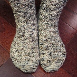 May include: A pair of grey and brown patterned socks with a textured knit. The socks are made of a soft, comfortable material.