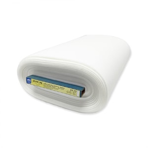 May include: A roll of white fabric, possibly interfacing or stabilizer, is shown. The fabric is tightly rolled, revealing layers of material. A blue and brown label with text is visible on the roll, indicating the product's name and specifications.