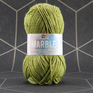 May include: A ball of green yarn with a label that reads "MARBLE" and "80% MERINO WOOL // 20% SILK DK WEIGHT". The yarn is a light green color and appears to be soft and textured. The label has a colorful design.