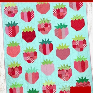 Puede incluir: Un patrón de edredón de retazos de fresas con un fondo azul claro y diseños de fresas rojas. El patrón del edredón mide 157 cm por 208 cm. El texto en el edredón dice "Strawberry Patch Quilt Pattern" y "Great for Scraps".