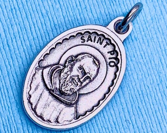 May include: Silver oval pendant with a depiction of Saint Pio, the words "SAINT PIO" are inscribed around the image.