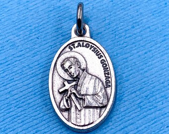 May include: Silver oval-shaped pendant with a depiction of Saint Aloysius Gonzaga holding a cross. The pendant has the text "ST. ALOYSIUS GONZAGA" around the edge.