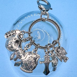 May include: Silver keychain with multiple charms, including a helmet, shield, sword, and eagle. The charms are attached to a silver ring and a silver clasp.