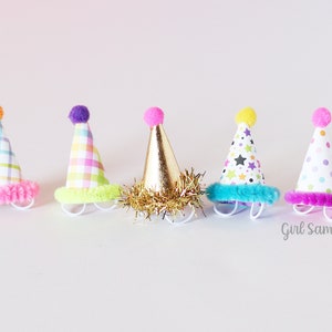 May include: Five colorful party hats with different patterns and pom-poms on top. The hats are made of paper and have a fuzzy trim around the bottom.